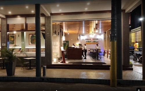 Stella Artois bar interior with staff, high-top tables, and outdoor seating at night.