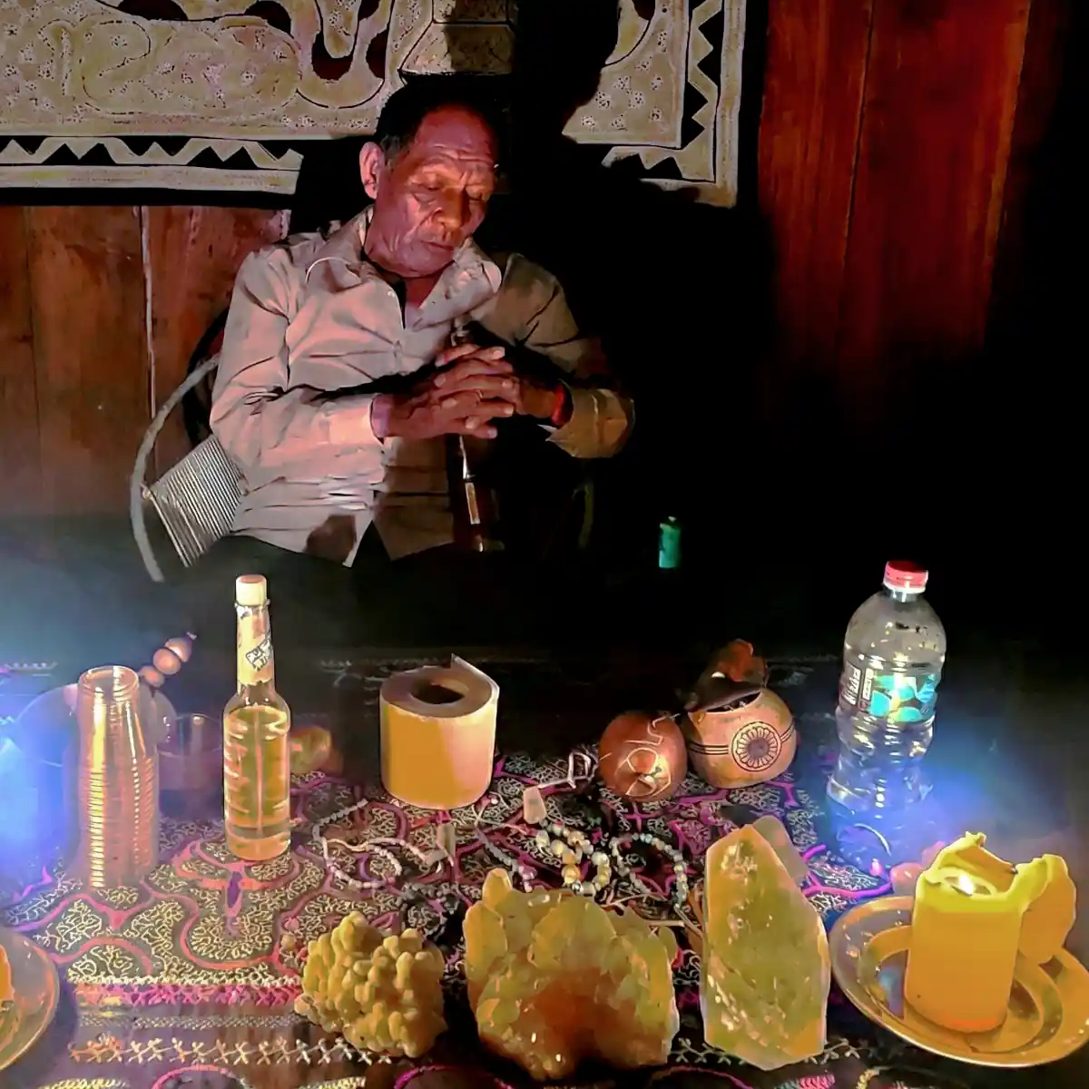 Manain at the alter in maloca before ceremony.  Lit candles, crystals on alter, dark